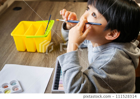 A boy drawing on white paper using paints A boy drawing on white paper using paints 111528314