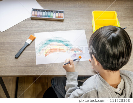 A boy drawing on white paper using paints 111528368