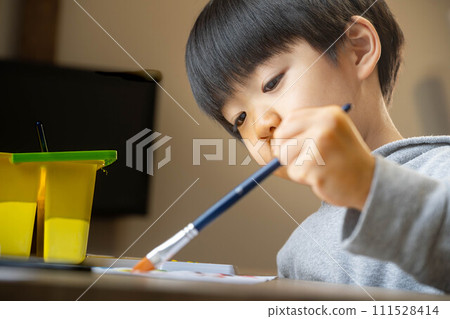 A boy drawing on white paper using paints A boy drawing on white paper using paints 111528414