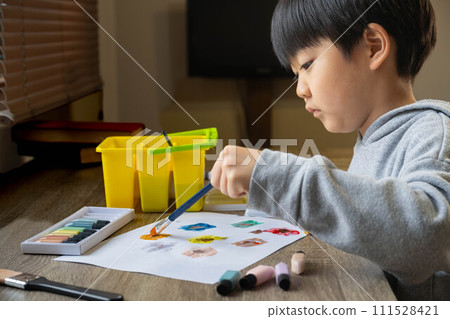 一個男孩用顏料在白紙上畫畫 111528421