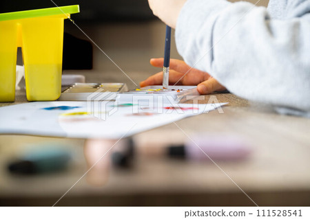 A child drawing on white paper using paints A child drawing on white paper using paints 111528541