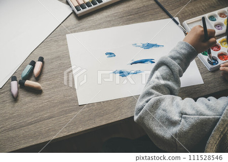 A child drawing on white paper using paints A child drawing on white paper using paints 111528546
