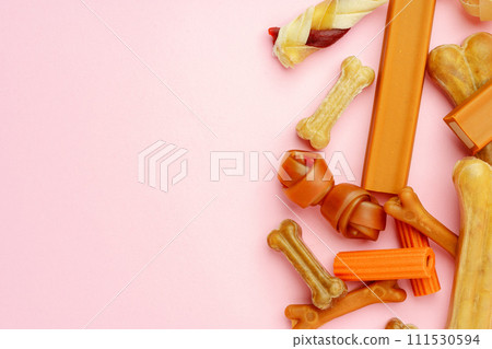 Dog chew bone and sticks on pink background 111530594