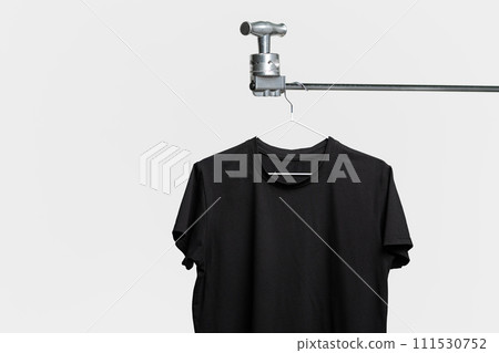 Plain black T-shirt hanging on hanger on gray background 111530752