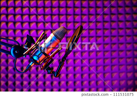 Professional studio microphone against acoustic foam panel background in neon light 111531075