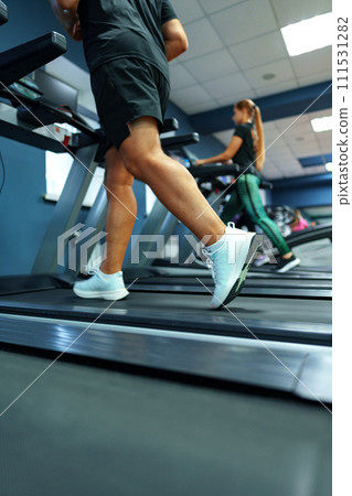 Fit man running on treadmill in a gym 111531282