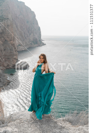 Woman sea green dress. Side view a happy woman with long hair in a long mint dress posing on a beach with calm sea bokeh lights on sunny day. Girl on the nature on blue sky background. Woman sea green dress. Side view a happy woman with long hair in a long mint dress posing on a beach with calm sea bokeh lights on sunny day. Girl on the nature on blue sky background. 111531377
