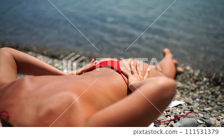 Woman taking red bikini off on beach for tan, lady stripping holiday swimsuit with bow in string. Fun and relax, sexy model untying swimming costume bra, happy woman in swimwear on vacation 111531379