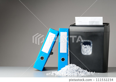 Office paper shredder on table against gray background Office paper shredder on table against gray background 111532234