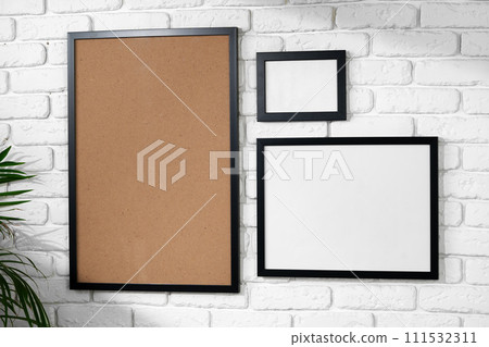 Black picture frame hanging on white brick wall copy space Black picture frame hanging on white brick wall copy space 111532311