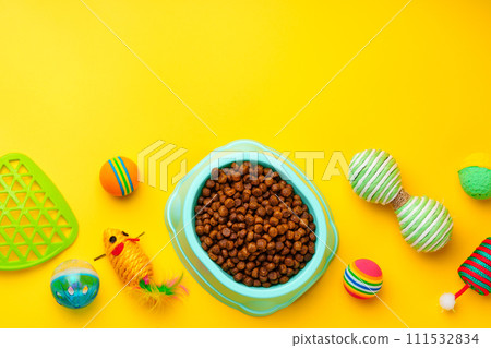 Cat bowl with dry food and toys on yellow background studio shot Cat bowl with dry food and toys on yellow background studio shot 111532834