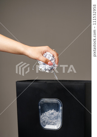 Hand using paper shredding machine against gray background Hand using paper shredding machine against gray background 111532958