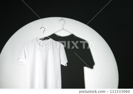 Blank T-shirt hanging in a spotlight in studio Blank T-shirt hanging in a spotlight in studio 111533060