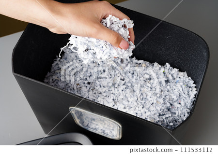 Hand using paper shredding machine against gray background 111533112