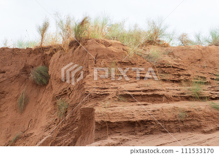 Sand quarry with layers of clay and sand and grass, material extraction. Copy space Sand quarry with layers of clay and sand and grass, material extraction. Copy space 111533170