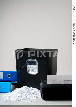 Office paper shredder on table against gray background Office paper shredder on table against gray background 111533579