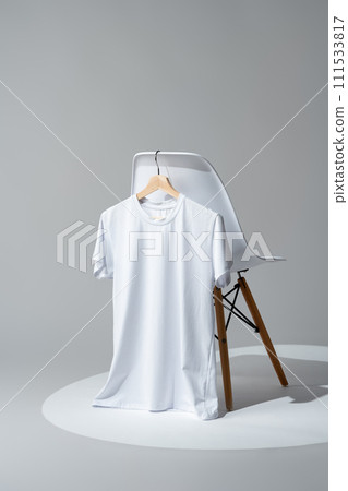 White blank t-shirt hanging on chair in empty room White blank t-shirt hanging on chair in empty room 111533817