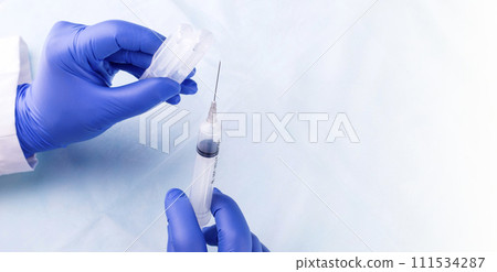 Medical gloved hands holding syringe with a bead of liquid emerging testing the function of the syringe Medical gloved hands holding syringe with a bead of liquid emerging testing the function of the syringe 111534287