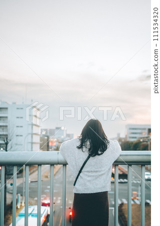一個女孩從人行天橋上看城市和日落 一個女孩從人行天橋上看城市和日落 111534320