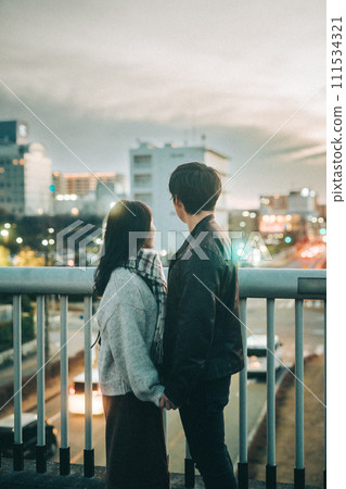 Rear view of a couple looking at the night view from the pedestrian bridge Rear view of a couple looking at the night view from the pedestrian bridge 111534321