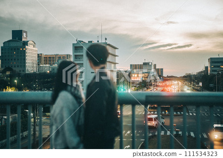 Rear view of a couple looking at the night view from the pedestrian bridge 111534323