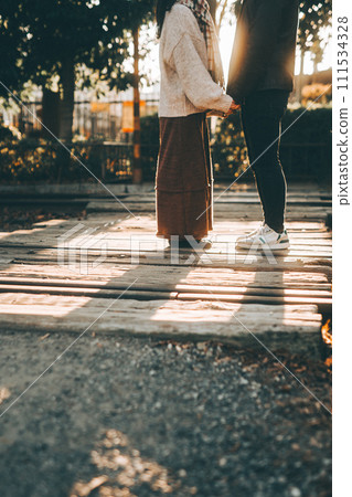 夕陽下的秋季公園裡，一對情侶的腳面對面 111534328