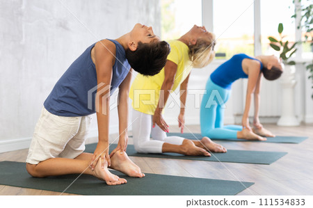 Grandmother, mother and teen son do camel pose Ushtrasana in gym Grandmother, mother and teen son do camel pose Ushtrasana in gym 111534833
