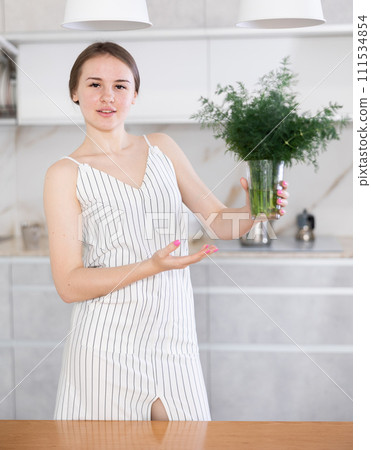 Young girl demonstrating a bunch of fennel put in glass in the kitchen 111534854