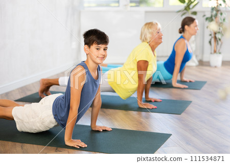 Preteen boy practicing upward facing dog pose of yoga in fitness room Preteen boy practicing upward facing dog pose of yoga in fitness room 111534871