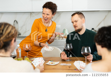 Happy group of friends playing poker cards and drinking wine Happy group of friends playing poker cards and drinking wine 111535053