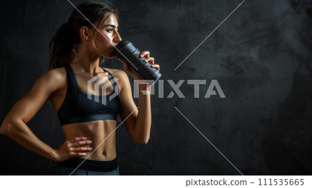 athletic woman, with defined muscles wearing sportswear, drinking a protein shake 111535665
