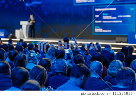 Speaker presenting at tech conference with audience captivated Speaker presenting at tech conference with audience captivated 111535935