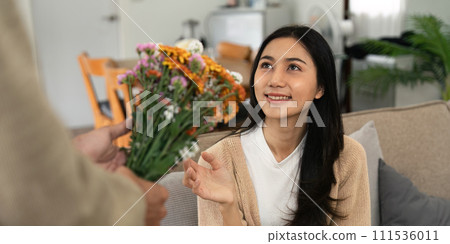 Romantic young asian couple embracing with holding flowers and smiling in living room at home. fall in love. Valentine concept Romantic young asian couple embracing with holding flowers and smiling in living room at home. fall in love. Valentine concept 111536011