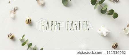 eucalyptus branches, eggs, feathers, ceramic bunny on light grey background 111536962