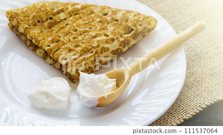 Pancake with sour cream for Maslenitsa on a white plate and napkin from burlap. Pancake with sour cream for Maslenitsa on a white plate and napkin from burlap. 111537064