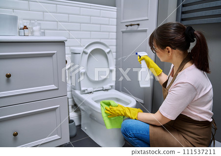 Woman in gloves apron using cleaning detergent clean toilet in bathroom 111537211