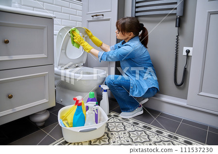 Woman in gloves using cleaning detergent clean toilet in bathroom Woman in gloves using cleaning detergent clean toilet in bathroom 111537230