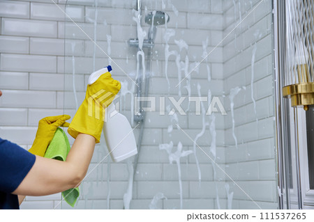 Close-up hands in gloves cleaning bathroom, washing glass in shower 111537265