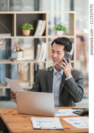 Happy asian business man have the joy of talking on the smartphone, tablet and laptop in the home office Happy asian business man have the joy of talking on the smartphone, tablet and laptop in the home office 111537470