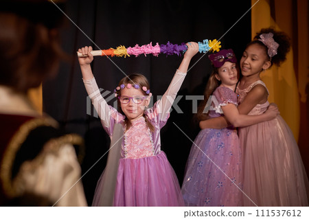 Portrait of cute little girl acting on stage as warrior princess wearing pink dress in school play copy space Portrait of cute little girl acting on stage as warrior princess wearing pink dress in school play copy space 111537612