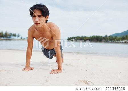 Active Asian Athlete Running on the Beach at Sunset: Fitness and Freedom 111537628