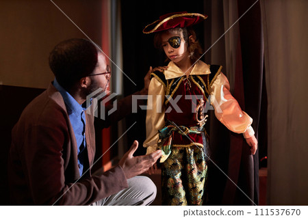 Side view portrait of caring drama teacher helping little boy ready to go on stage for school play copy space Side view portrait of caring drama teacher helping little boy ready to go on stage for school play copy space 111537670