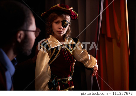 Waist up portrait of young boy wearing pirate costume standing by red curtain ready to go on stage in school play copy space Waist up portrait of young boy wearing pirate costume standing by red curtain ready to go on stage in school play copy space 111537672