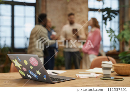 Background image of open laptop with stickers on wooden meeting table in coworking space 111537891