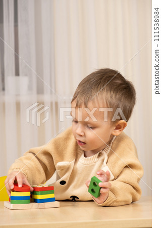 Little cute boy playing with toys while sitting at table 111538984