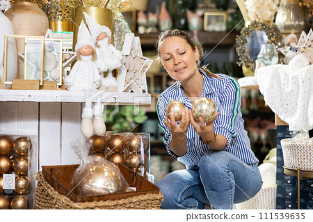 Cheerful woman selecting baubles in store 111539635