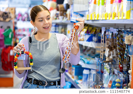 Young happy woman choosing toys for pets in pet shop 111540774