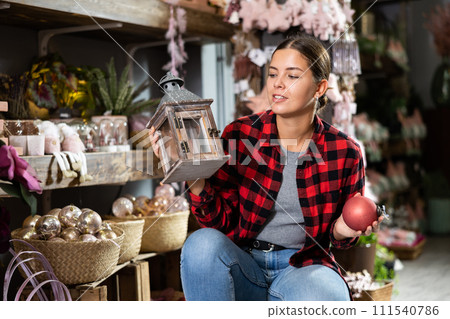 Cheerful young female in casual shirt buying Christmas bulbs before holidays in a store Cheerful young female in casual shirt buying Christmas bulbs before holidays in a store 111540786