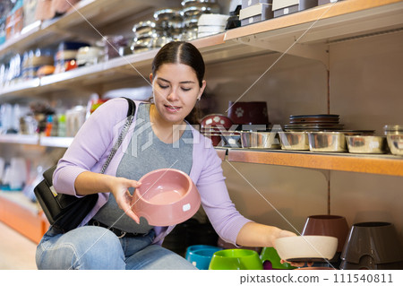Young woman choosing bowl for puppy in pet supplies store Young woman choosing bowl for puppy in pet supplies store 111540811