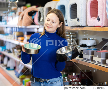 Cheerful woman buying bowl for pets in pet store 111540902